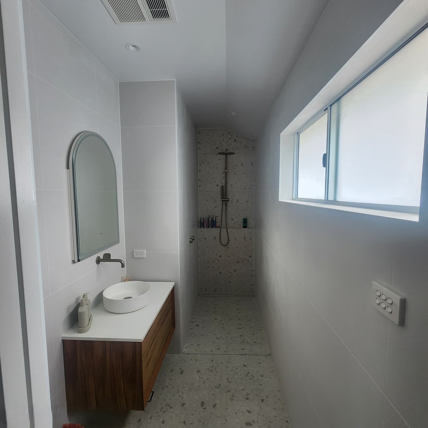 Bathroom with an arched mirror and a built-in shower
