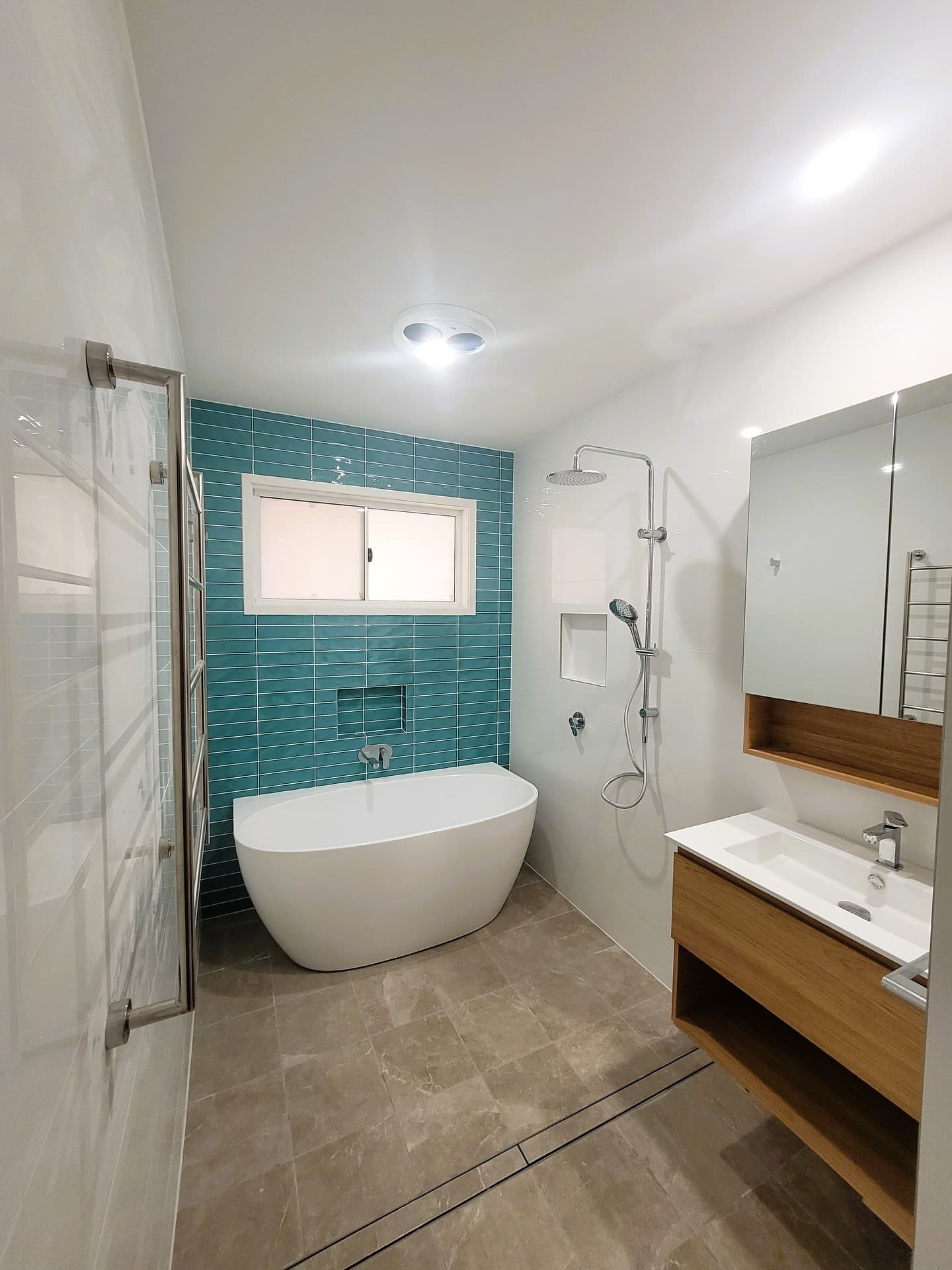 Teal feature-tile wall behind a freestanding bath
