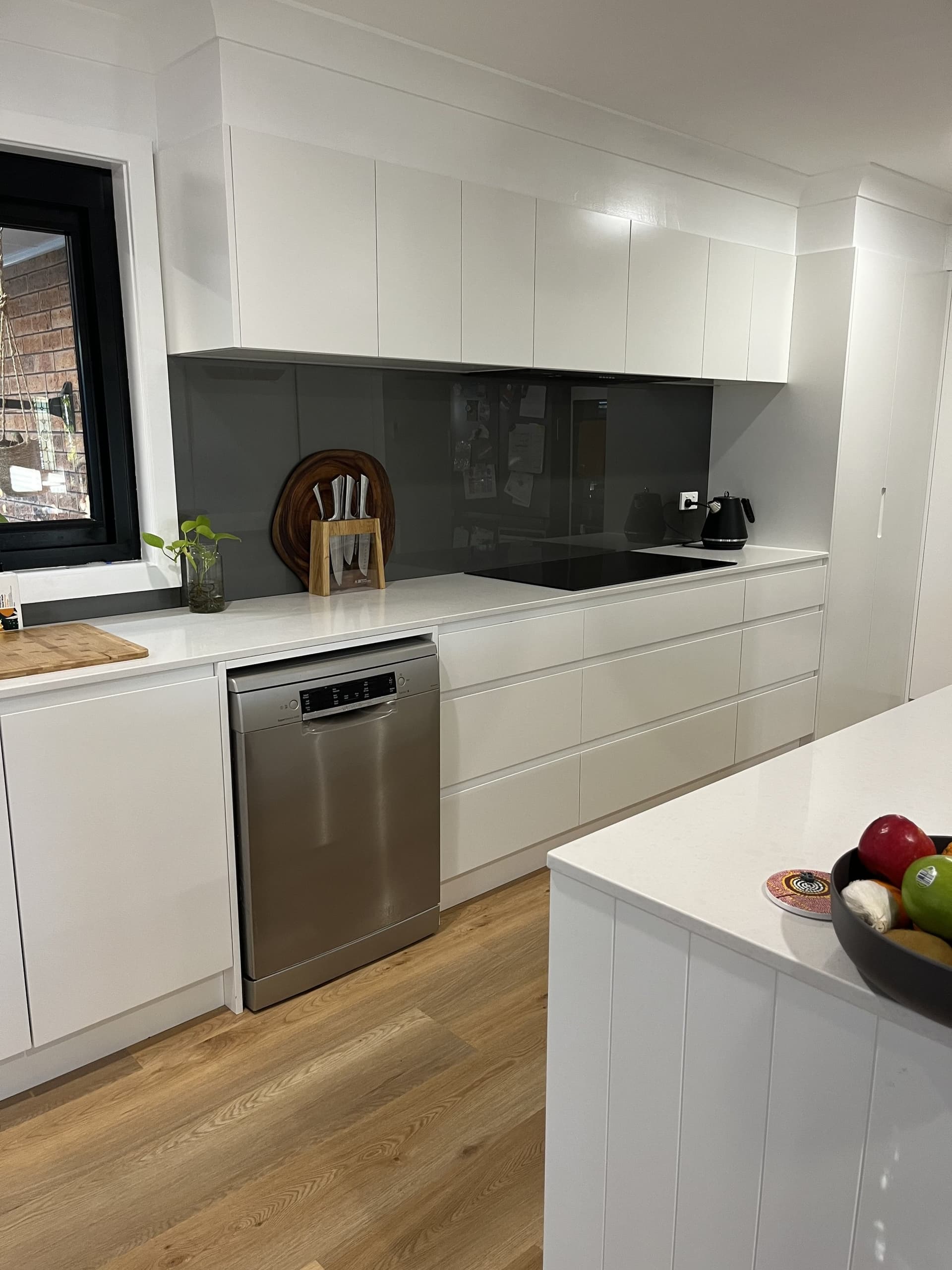 White kitchen with a stone island and dark splashback
