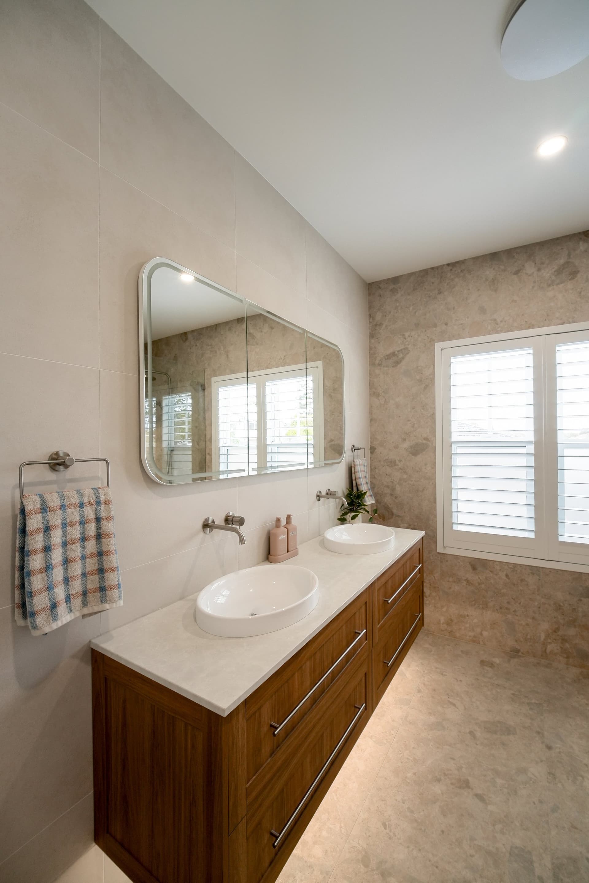 Double vanity in warm timber with a natural stone top