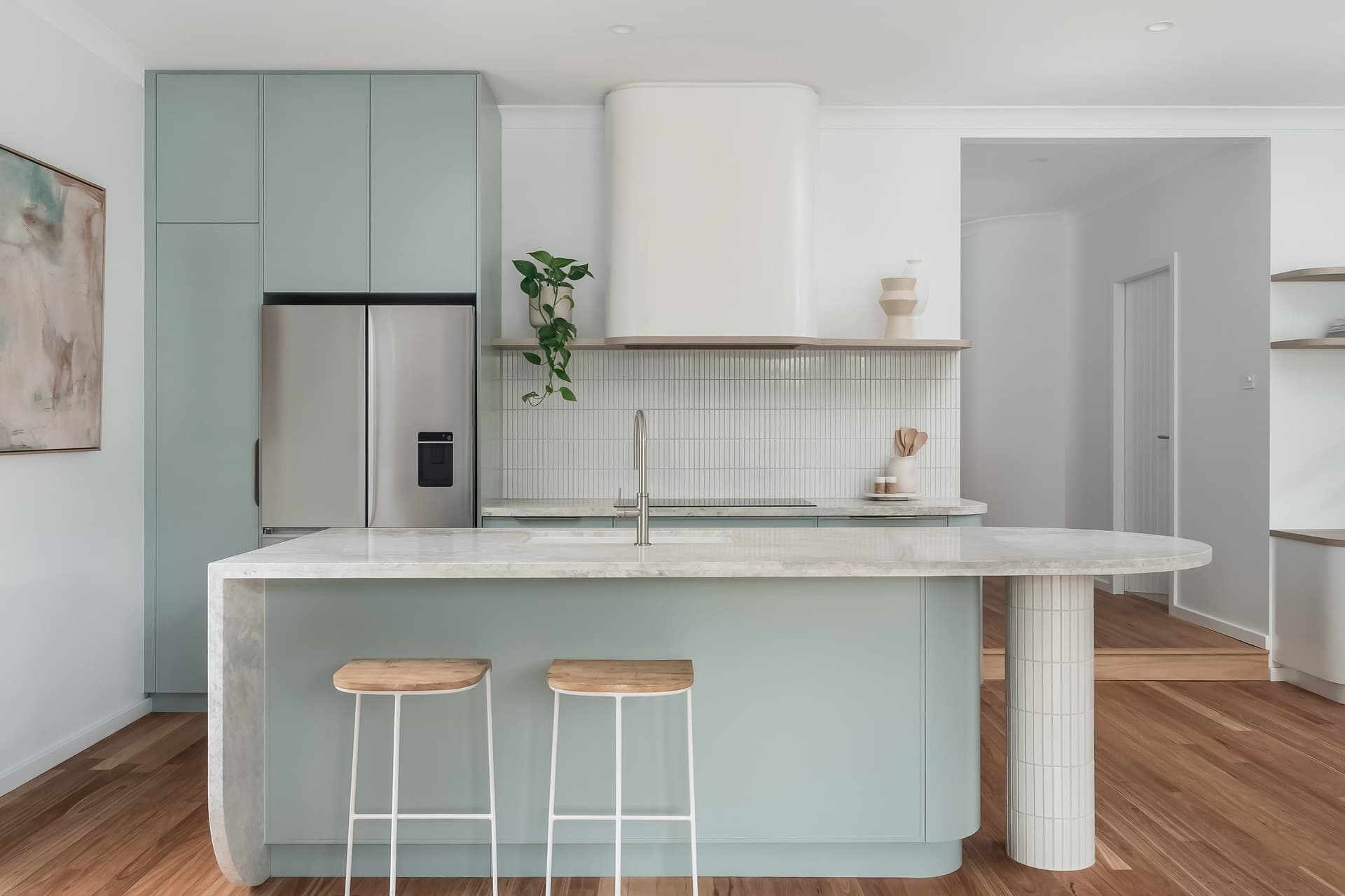 Curved stone island and sage joinery in the Adamstown renovation by Delaney Construction Projects